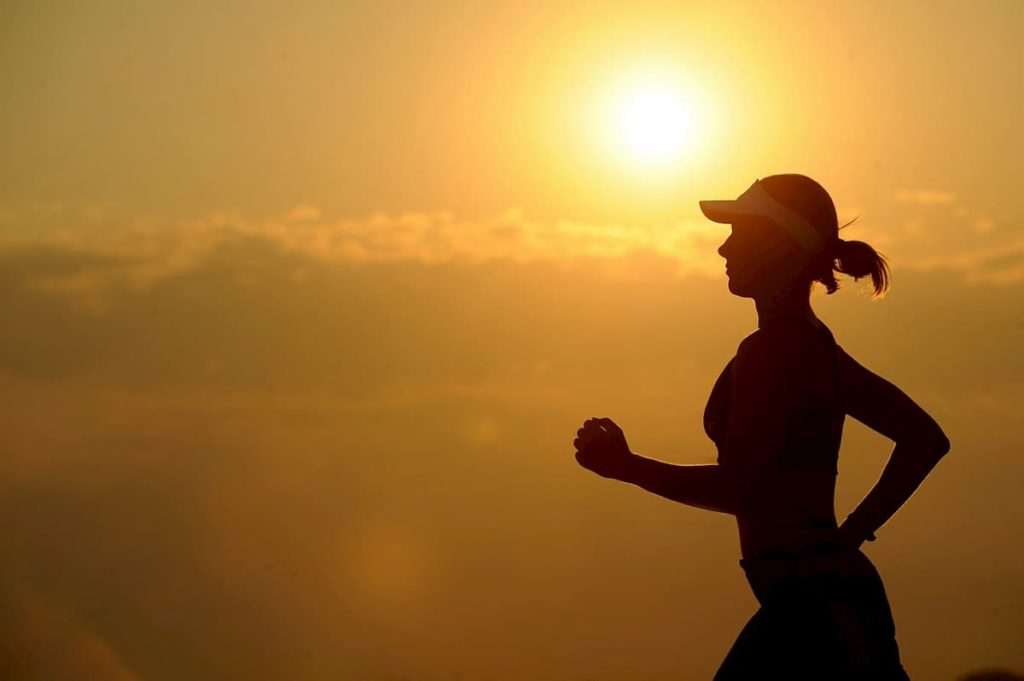 A person silhouetted, running with the sun setting behind them
