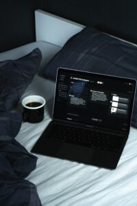 Dark mode on a black laptop sitting on top of a bed.