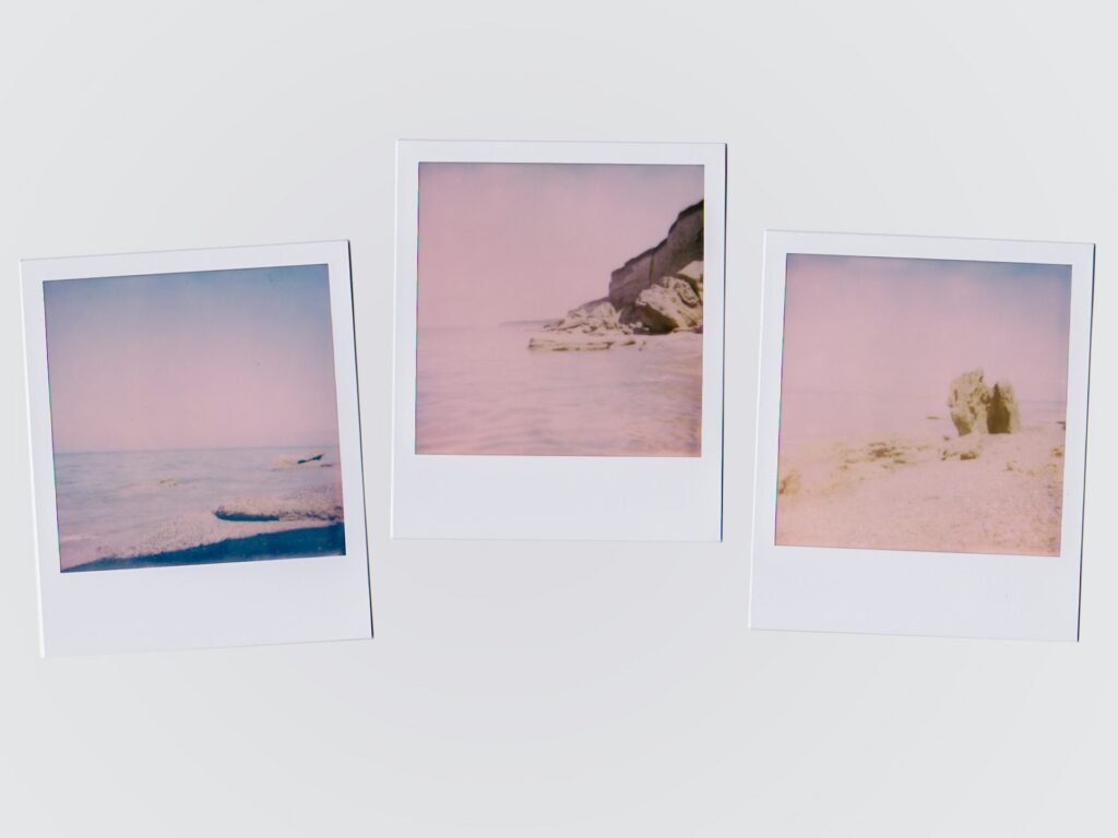 Three polaroids of a beach scene laying on a white table.